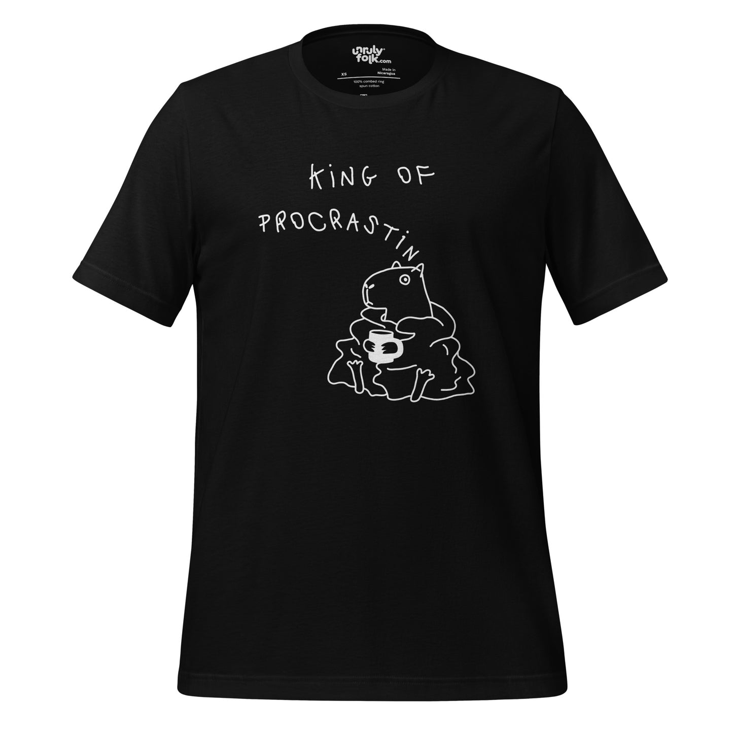 The image is a black t-shirt with a drawing of a capybara wearing a blanket and holding a mug, looking cosy. The design features the words "KING OF PROCRASTINATION". Unruly Folk brand.
